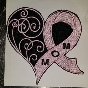 May include: Embroidered heart-shaped patch with a black background and a pink ribbon. The heart features a swirling design on the left side. The pink ribbon has the word "MOM" embroidered on it.
