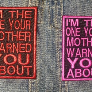 May include: Two embroidered patches with the text "I'M THE ONE YOUR MOTHER WARNED YOU ABOUT". One patch has red text and border, the other has pink text and border. Both are on a denim background.