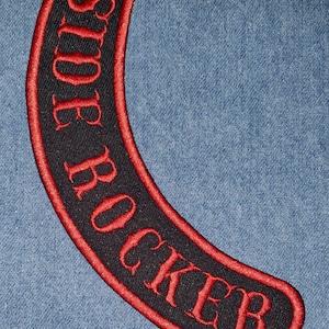 May include: A black and red embroidered patch with the text "SIDE ROCKER" in a curved shape.
