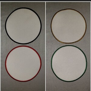 May include: Four circular patches with white centers and colored borders. The borders are black, gold, red, and green. The patches are blank, ready for customization, and are likely for clothing or accessories.