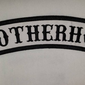 May include: Embroidered patch with the word "BROTHERHOOD" in black, arched across a white background. The patch has a black border. The text is in a bold, stylized font.