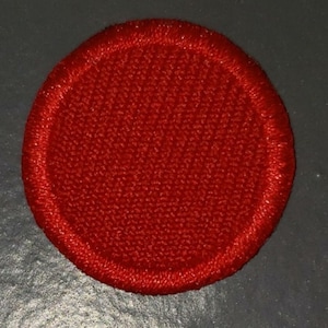 May include: A solid red circle patch with a stitched edge.