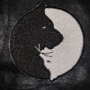 May include: Embroidered patch featuring a Yin and Yang design with two cat silhouettes, one black and one white. The patch is circular and set against a black background, likely leather or a similar material.