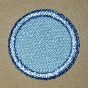 May include: A light blue round patch with a dark blue double stitched border.
