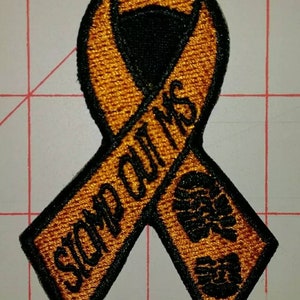May include: Orange ribbon with black stitching and the text "Stop Outing Us" in black. The ribbon has a black footprint design on the bottom.