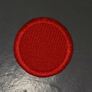 May include: A red circle patch with a stitched edge.