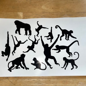 May include: Black silhouette of a gorilla and several monkeys in various poses on a white background.