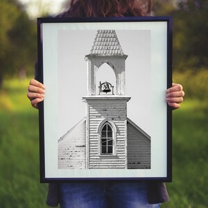 May include: A framed black and white photograph of a weathered church steeple with a bell in the belfry.