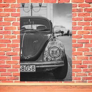 Op de afbeelding: Een zwart-witfoto van een vintage Volkswagen Kever met een kentekenplaat waarop "38058" staat. De auto staat geparkeerd op straat en de koplamp is scherp in beeld.