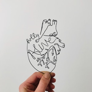 May include: Wire sculpture of a heart with the word "truly" and the word "alive" written inside the heart.