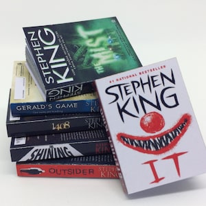 Pode incluir: Uma pilha de livros de bolso de Stephen King, incluindo "The Mist", "Gerald's Game", "1408", "The Shining", "The Outsider" e "IT".