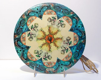 May include: A round, psychedelic record with a swirling blue and black marbled design. The center of the record features a kaleidoscope of images of children holding flowers. The text "Peter Max" is printed on the record.