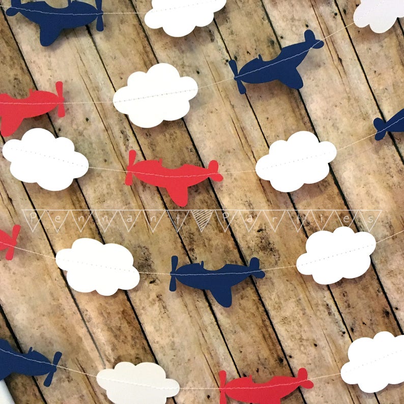 Pode incluir: Uma guirlanda de avi&otilde;es de papel vermelho, branco e azul com nuvens. A guirlanda &eacute; perfeita para um ch&aacute; de beb&ecirc; ou uma festa de anivers&aacute;rio.