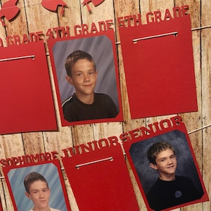 May include: Red graduation banner with red paper frames for photos. The banner has the words "1st Grade", "4th Grade", "5th Grade", "Sophomore", "Junior", and "Senior" printed on it.