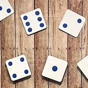 May include: A string of white dice with blue dots hangs against a woodgrain background. Each die has a different number of dots, from one to six.