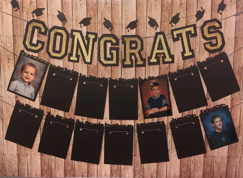 May include: A graduation-themed banner with the word "CONGRATS" in gold glitter letters. The banner includes black photo holders with grade labels and student photos, all against a wood-grain background.