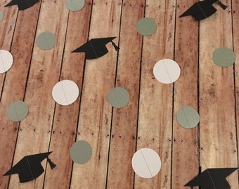 May include: A graduation party garland with black graduation caps and white and green paper circles.