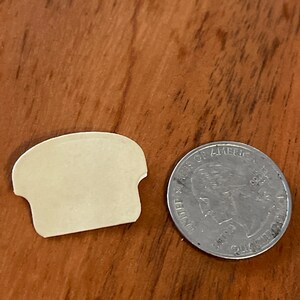 May include: A white bread sticker shaped like a slice of bread. The sticker is next to a US quarter.