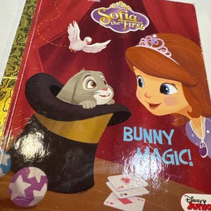 May include: A Little Golden Book featuring Disney Junior's Sofia the First. The cover shows Sofia the First with a crown, smiling and looking at a bunny rabbit that is popping out of a top hat. The text on the cover reads "Bunny Magic!"