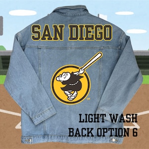 May include: Light wash denim jacket with a yellow and black San Diego Padres logo on the back. The logo features a cartoon character swinging a baseball bat. The text "LIGHT WASH BACK OPTION 6" is printed below the logo.