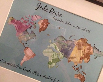 May include: Framed world map art print with a light blue background. The map is composed of colorful currency, with text in German that reads "Jede Reise beginnt mit dem ersten Schritt..." and "Wir wünschen Euch alles erdenklich Gute zur Hochzeit!"