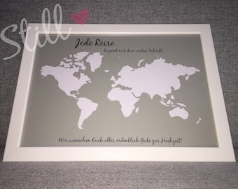 May include: A white framed picture with a gray background and a white outline of a world map. The text "Jede Reise beginnt mit dem ersten Schritt..." is printed above the map. The text "Wir wünschen Euch alles erdenklich Gute zur Hochzeit!" is printed below the map.