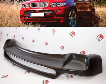 May include: A black plastic car bumper diffuser for a BMW X5. The diffuser has a smooth, rounded design with two small vents on the sides.