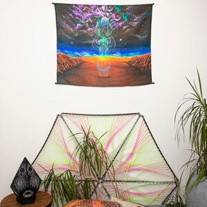 Puede incluir: Un tapiz con un dise&ntilde;o psicod&eacute;lico de un orbe brillante en un paisaje des&eacute;rtico con un cielo estrellado. El tapiz est&aacute; colgado en una pared blanca sobre una pieza de arte de cuerda.