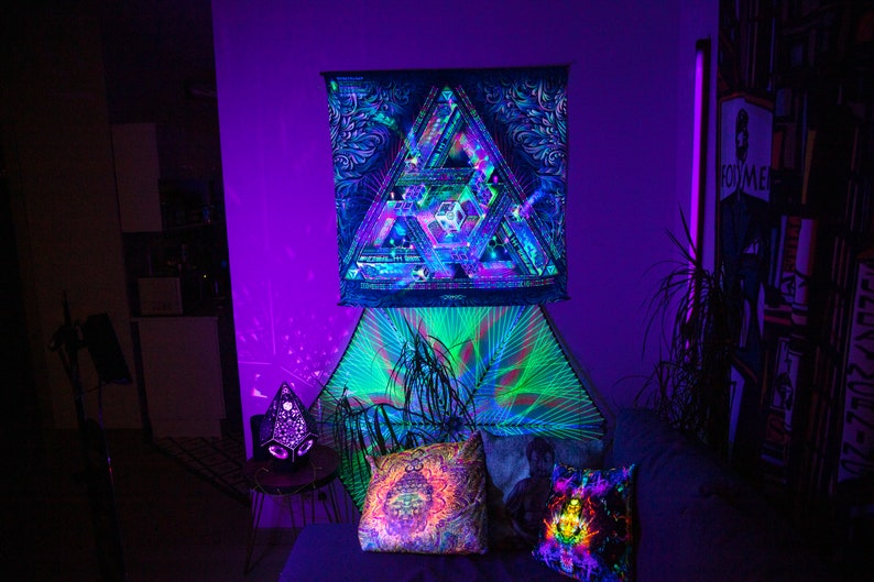 Peut inclure: Une chambre &agrave; coucher avec une tapisserie psych&eacute;d&eacute;lique accroch&eacute;e au mur. La tapisserie est un triangle noir et vert avec un motif g&eacute;om&eacute;trique. Il y a deux oreillers sur le lit, l'un avec un motif de mandala color&eacute; et l'autre avec un motif arc-en-ciel. La pi&egrave;ce est &eacute;clair&eacute;e par des lumi&egrave;res violettes et bleues.