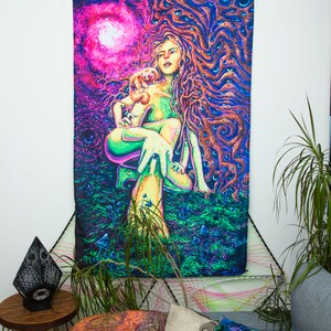 May include: A psychedelic tapestry featuring a woman with long flowing hair and a small animal in her arms. The woman is surrounded by swirling patterns and vibrant colors, including pink, purple, green, and blue. The tapestry is a vibrant and colorful piece of art that would add a unique touch to any room.