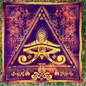 May include: A purple and gold tapestry with a geometric design. The design features a large eye in the center, surrounded by a triangle and other geometric shapes. The tapestry is bordered by a gold trim.