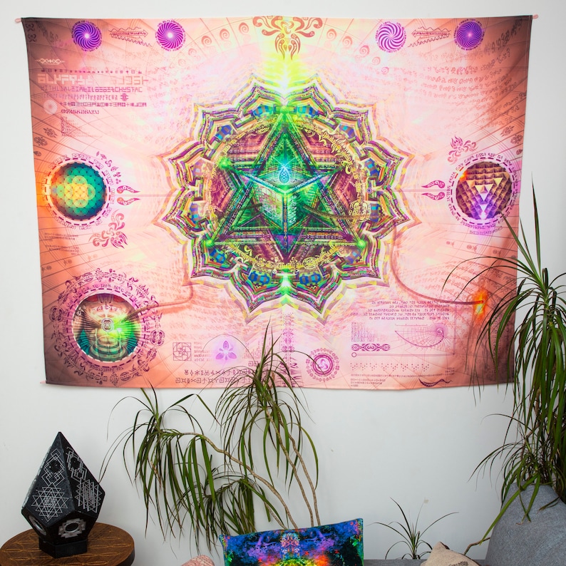May include: A tapestry with a pink background and a large, colorful mandala in the center. The mandala features a geometric design with a green triangle in the center. The tapestry is surrounded by a border of intricate patterns and symbols.