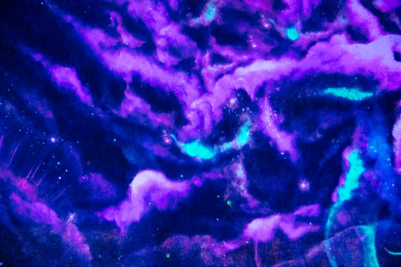 Puede incluir: Pintura abstracta de acuarela con matices azules y morados que se arremolinan, que se asemeja a una galaxia o nebulosa. El fondo es azul oscuro con puntos blancos dispersos.