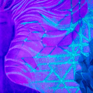May include: A close-up of a purple and blue abstract painting with a geometric pattern. The painting features a woman's face with her eyes closed and a flowing hair design.