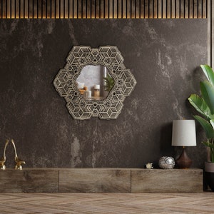 May include: A geometric patterned mirror hangs on a dark brown wall above a wooden shelf with a lamp, a decorative bowl, and a potted plant.