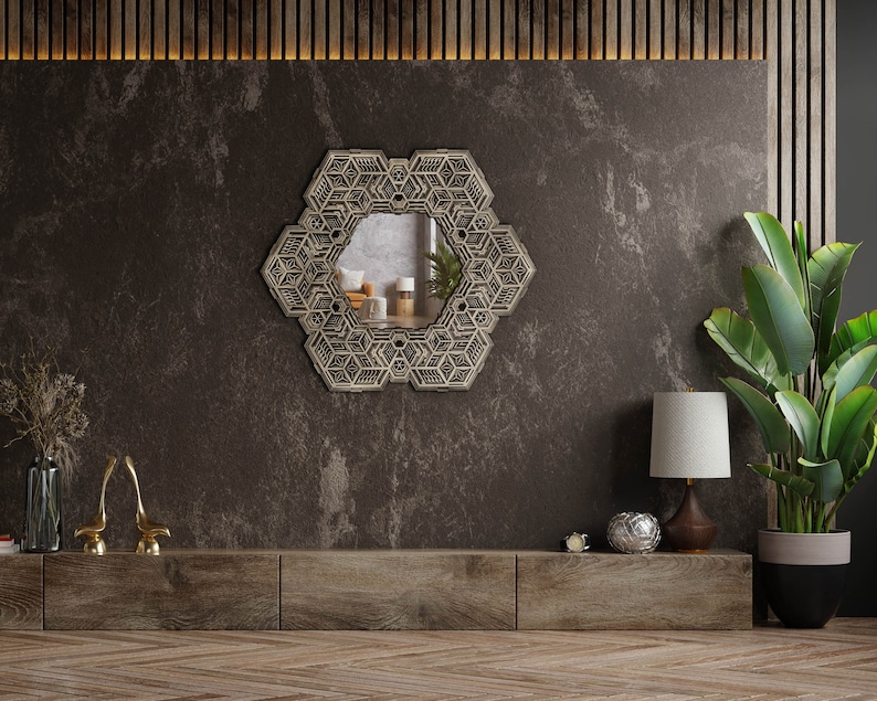 May include: A geometric patterned mirror hangs on a dark brown wall above a wooden shelf with a lamp, a decorative bowl, and a potted plant.