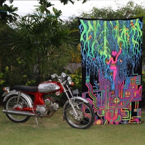 May include: A psychedelic tapestry with a vibrant green, blue, and pink color scheme. The tapestry features a woman standing in front of a complex, geometric design. The tapestry is hanging on a wall next to a red motorcycle.