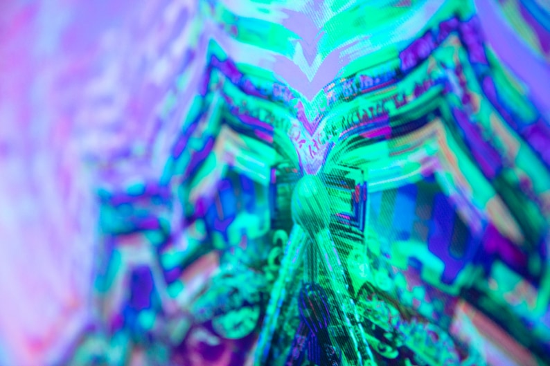 May include: Abstract digital art with a vibrant green, blue, and purple color scheme. The image is blurred and has a pixelated effect.