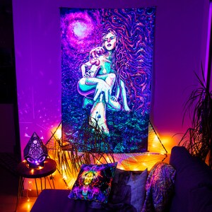 May include: A psychedelic tapestry featuring a woman with long flowing hair and a creature in her arms. The tapestry is in shades of blue, purple, and pink, with a swirling, abstract background.