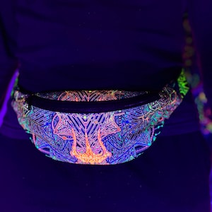 Puede incluir: Riñonera negra con un vibrante diseño geométrico en azul neón, naranja y verde. La bolsa tiene una cremallera negra y se lleva alrededor de la cintura. El diseño brilla bajo luz negra.