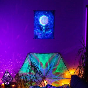 May include: A room decorated with a green and blue string art mandala, a black and white geometric light projector, and a tapestry with a glowing moon and stars. The walls are painted a deep purple.
