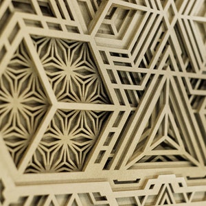 May include: A close-up of a wooden wall art piece with a geometric design. The design features intricate patterns of overlapping triangles and hexagons, creating a layered and textured effect.