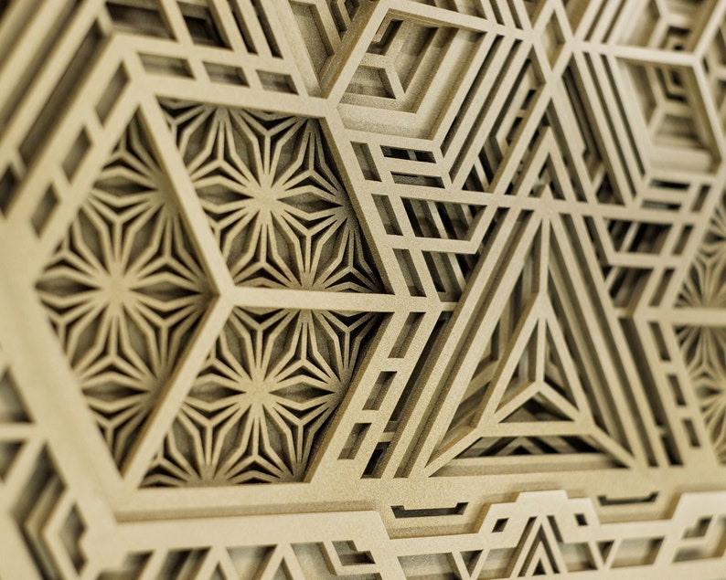 May include: A close-up of a wooden wall art piece with a geometric design. The design features intricate patterns of overlapping triangles and hexagons, creating a layered and textured effect.