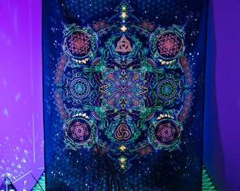 Op de afbeelding: Een zwarte wandkleed met een glow-in-the-dark ontwerp met een mandala met geometrische patronen en een sterrenhemel.