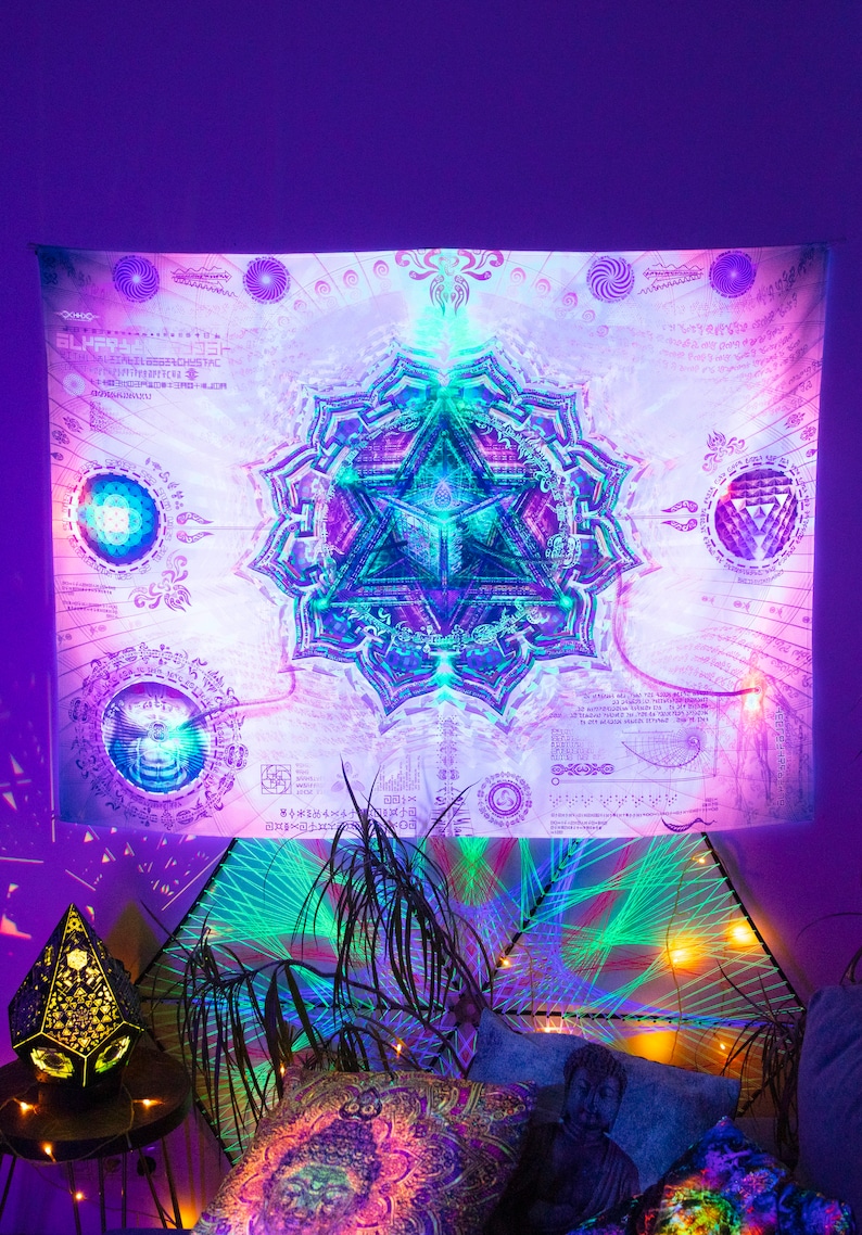 May include: A white tapestry with a colorful mandala design. The mandala features a triangle with a blue and green center and a purple and pink outer ring. The tapestry is surrounded by a white background with black text and symbols.
