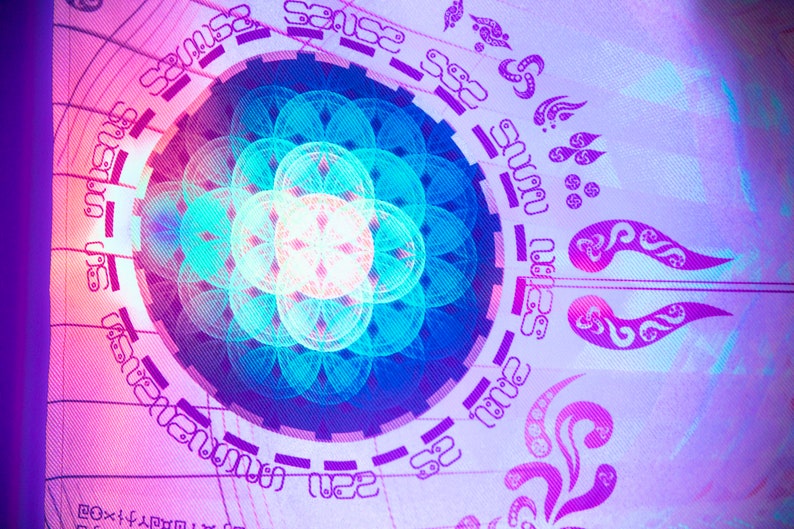 May include: A colorful, abstract design with a circular pattern and a flower-like shape in the center. The design is in shades of blue, pink, and white, and is surrounded by a ring of text.