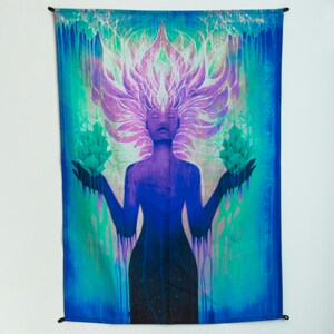 May include: A tapestry featuring a woman with a purple and green crown of leaves, holding two green crystals in her hands. The background is a blue and green gradient with a white and pink glow.
