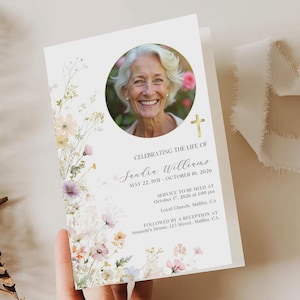 Peut inclure: Une carte de deuil avec une photo d'une femme souriante, ornée de motifs floraux. La carte contient le texte "Célébrer la vie de Sandie Williams" et les dates de naissance et de décès. Une croix dorée est visible.