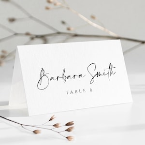 Puede incluir: Tarjeta de lugar blanca con caligrafía negra que dice "Barbara Smith" y "Mesa 6".