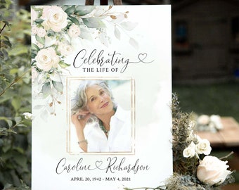 May include: A white floral memorial sign with a photo of a woman and the text "Celebrating the life of Caroline Richardson April 20, 1942 - May 4, 2021".